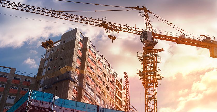 A crane is in the foreground of an urban setting.