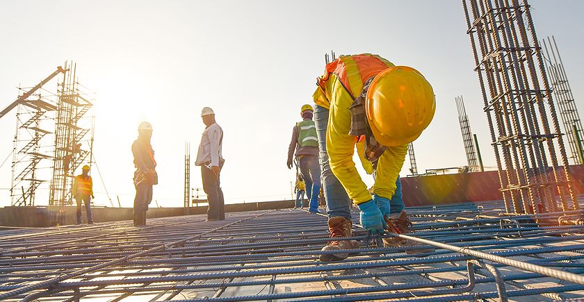 A group of construction workers standing on top of a building.