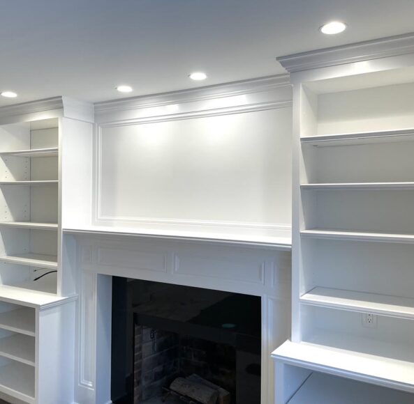 A fireplace with built in bookcases and lights.